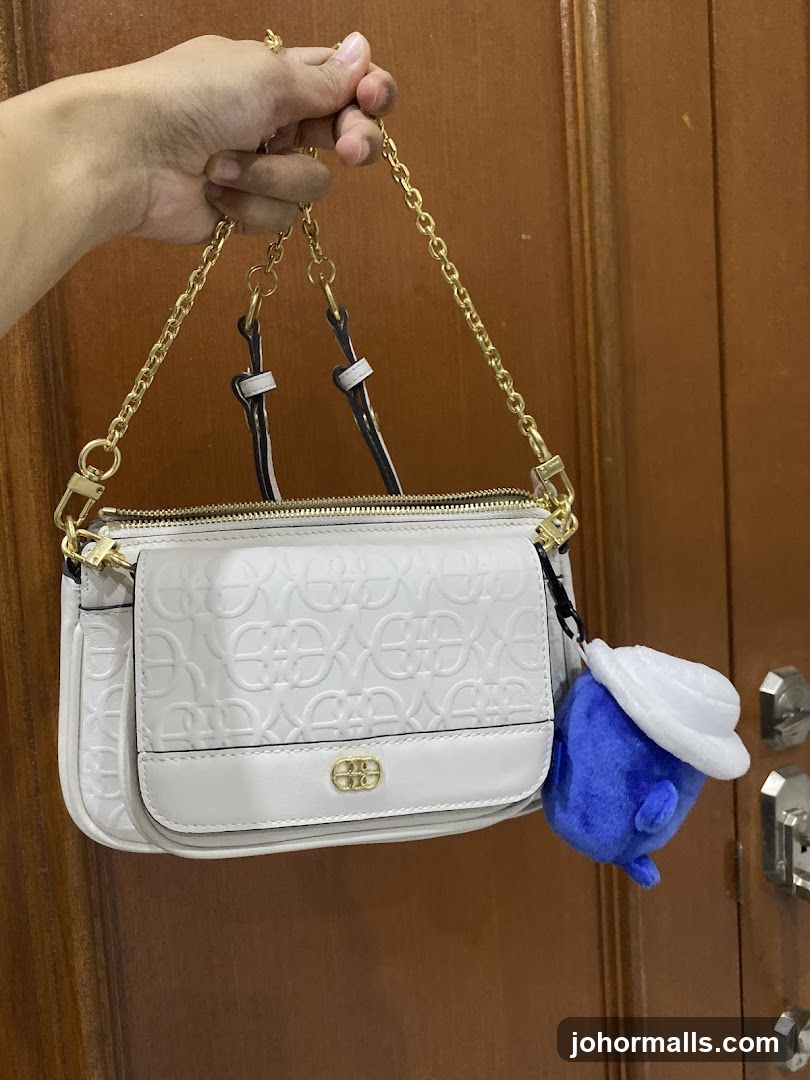 White handbag with embossed logo and blue plush charm