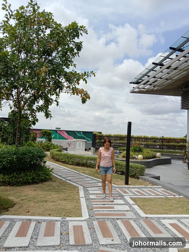 Woman walking on a paved path in a garden