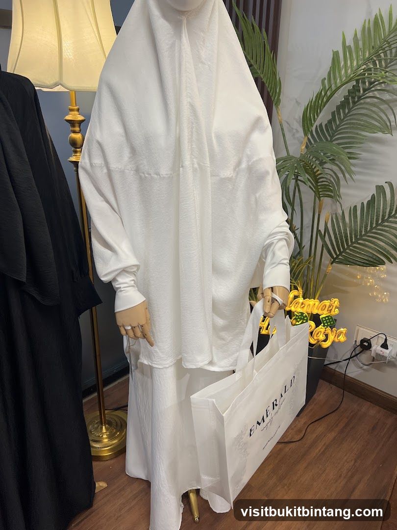 Mannequin in white prayer dress holding a shopping bag