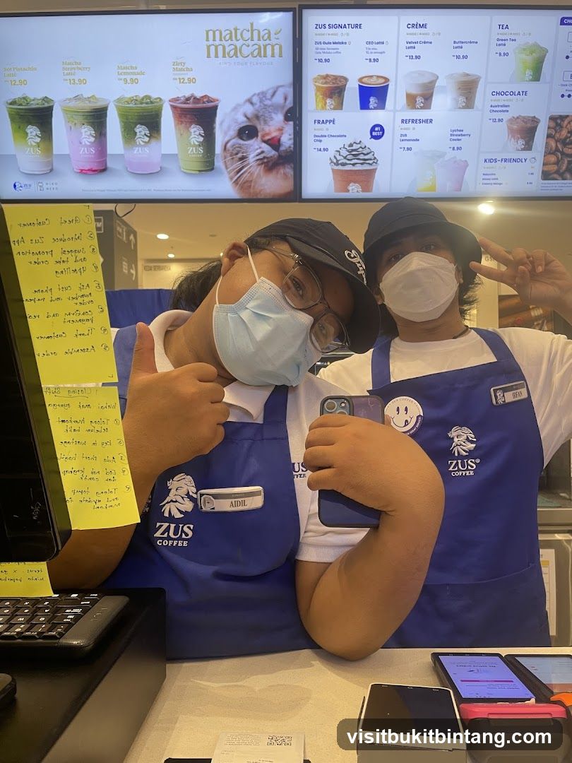Two employees posing for a photo at a ZUS Coffee counter