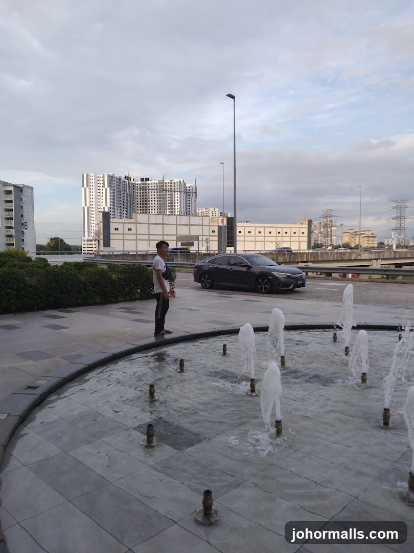 Man Standing by Fountain with Cityscape in Background