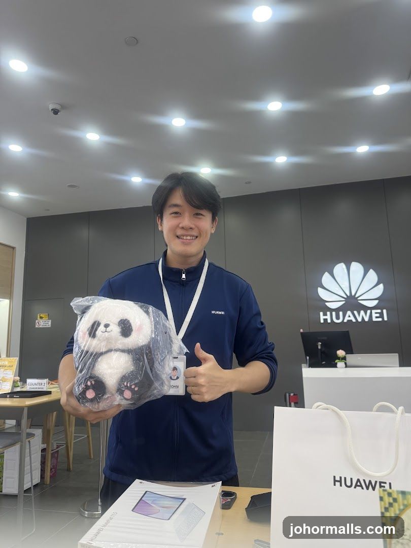 Employee holding a panda plush toy in a Huawei store
