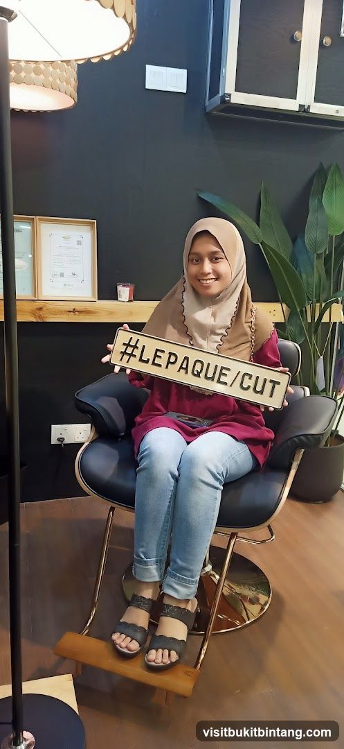 Woman holding a sign with #LEPAQUE/CUT