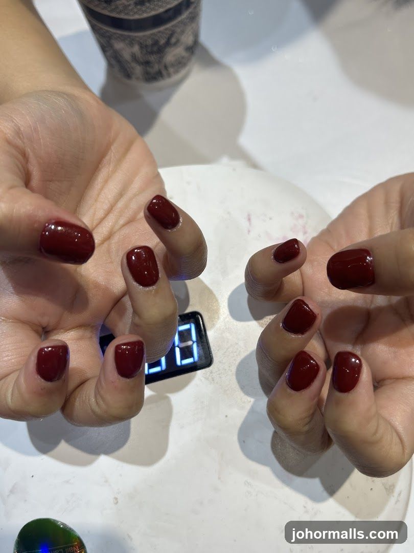 Hands with dark red nails under a UV lamp