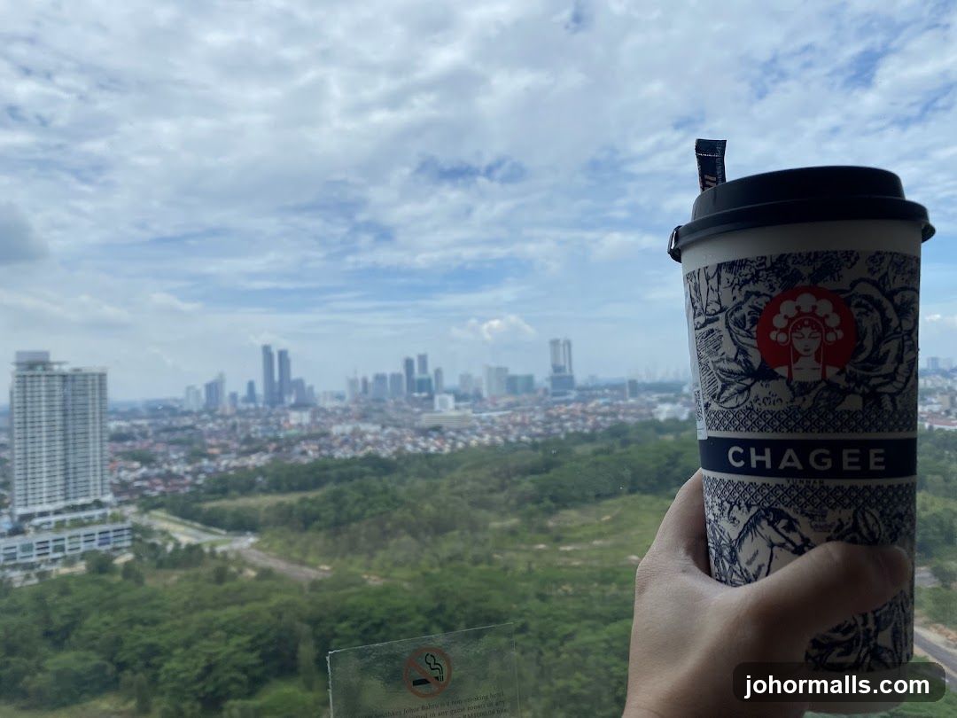 Hand holding beverage with cityscape view
