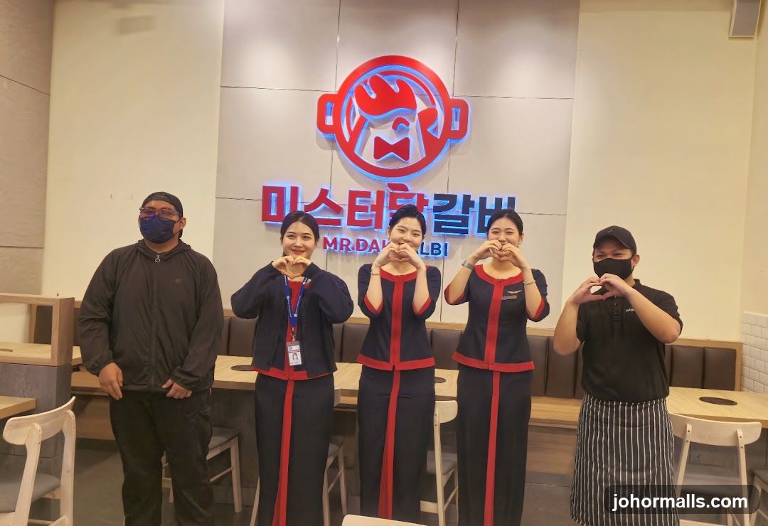 Staff posing in front of restaurant logo