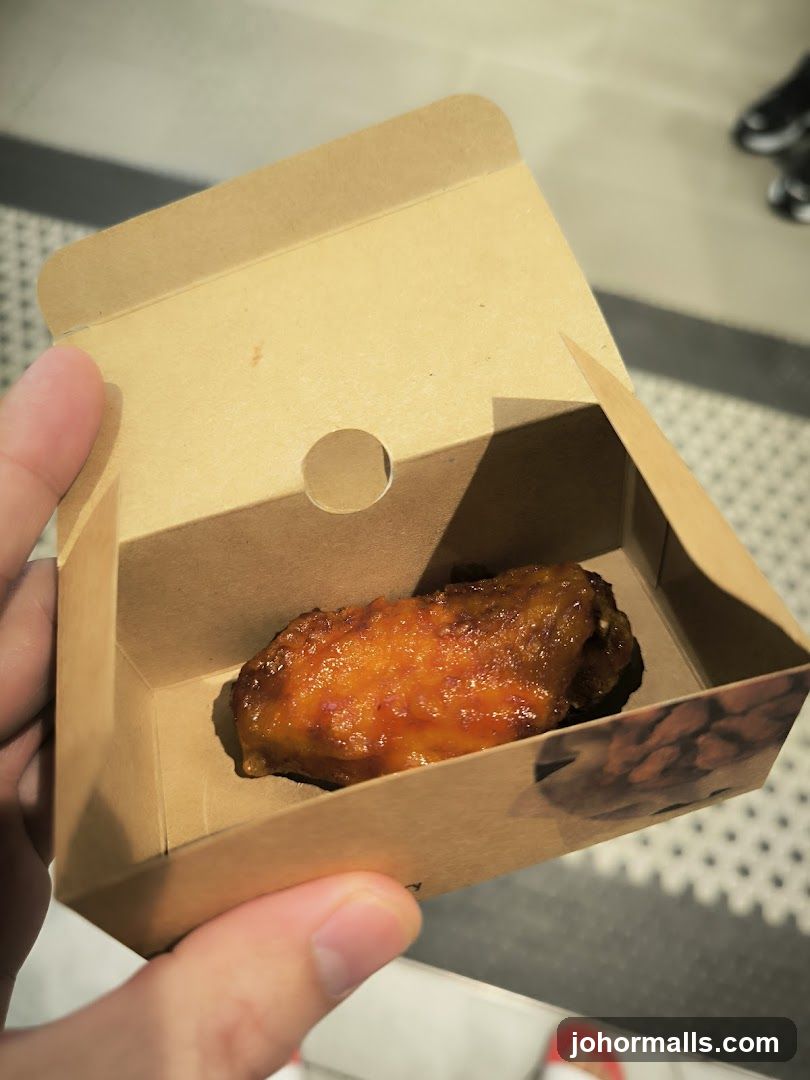 Hand holding chicken wing in cardboard box