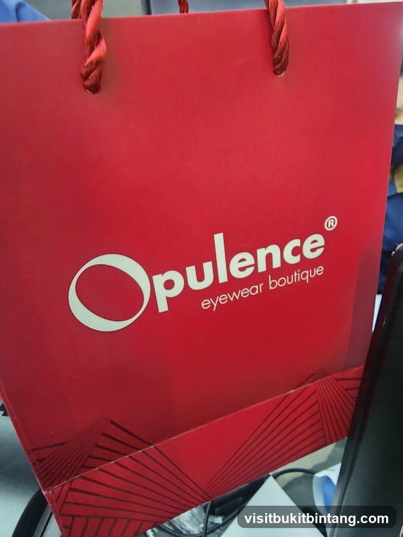 Red shopping bag with "Opulence eyewear boutique" logo