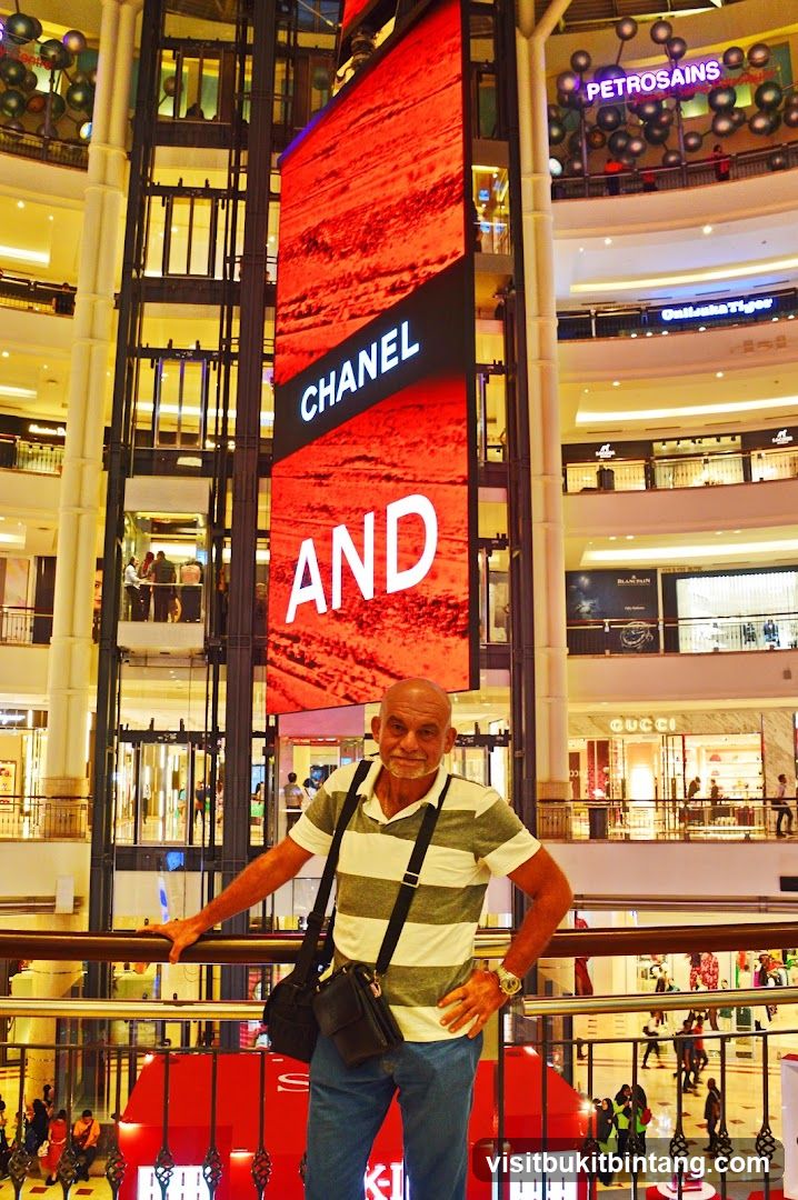 Man Posing in a Mall with a Large Digital Advertisement