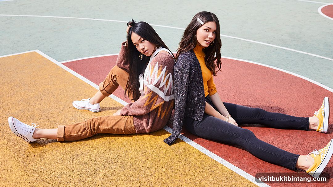 Two young women sitting on a colorful court