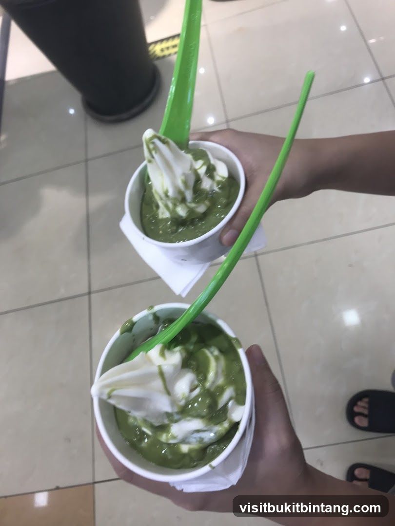 Two cups of soft serve ice cream with green topping
