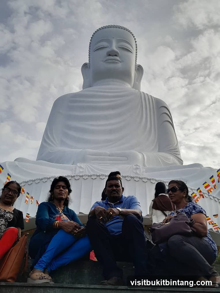People sitting in front of a large Buddha statue