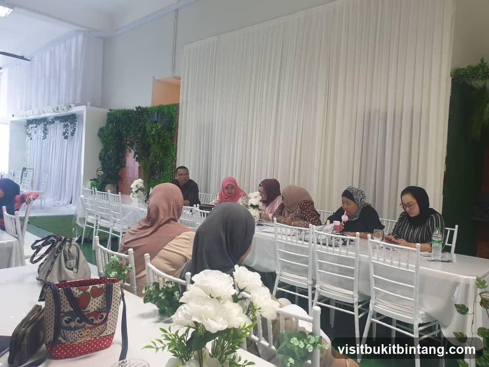 People seated at tables with white chairs and floral decorations