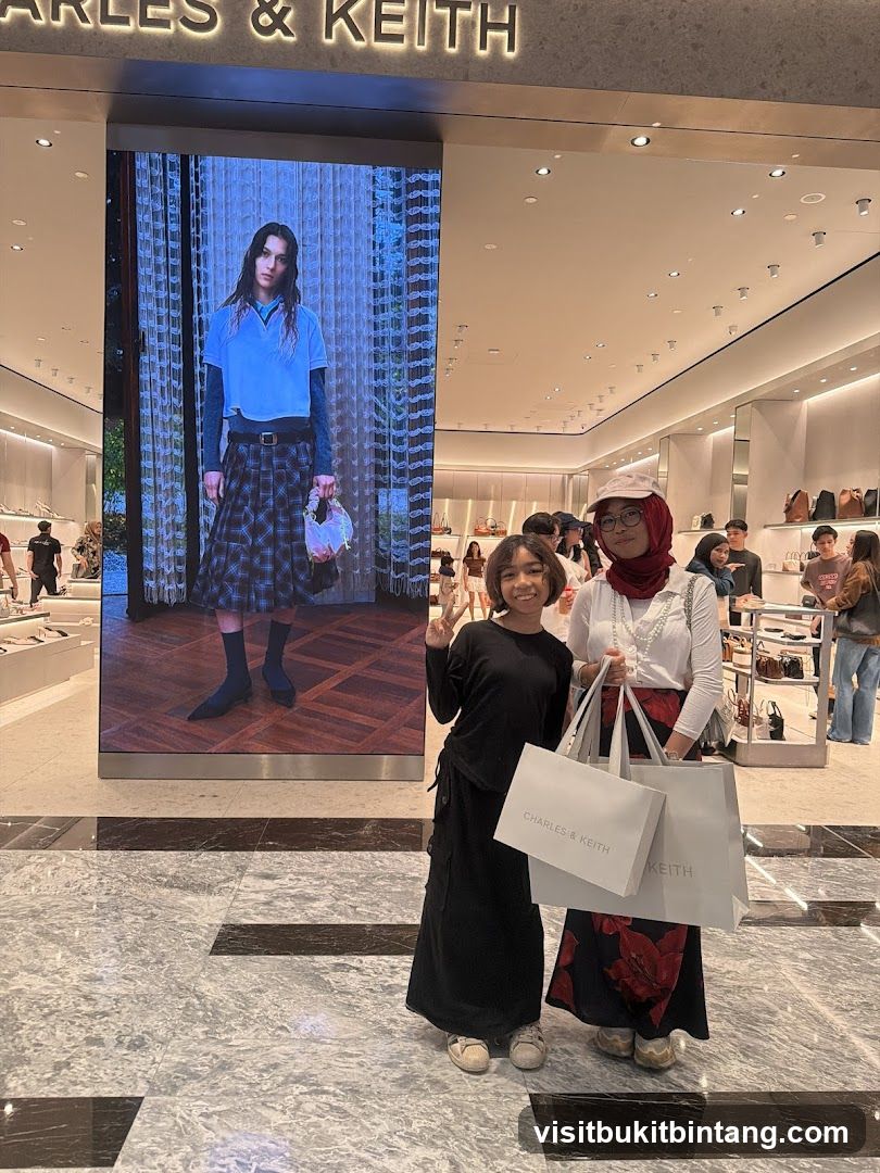 Two people posing in front of a Charles & Keith store display