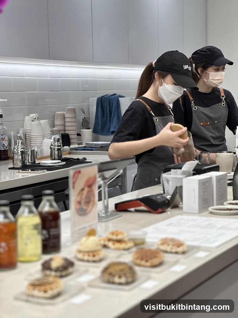 Baristas preparing drinks behind a counter with pastries