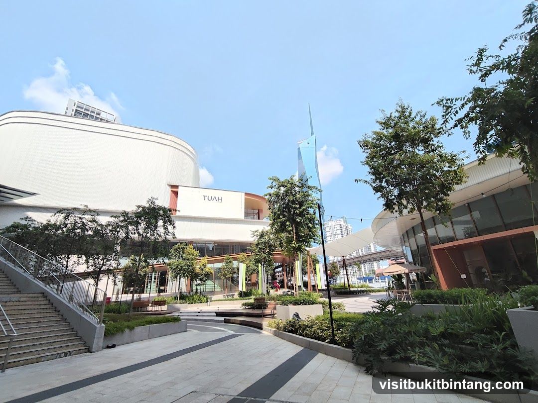 Modern outdoor plaza with shops and greenery