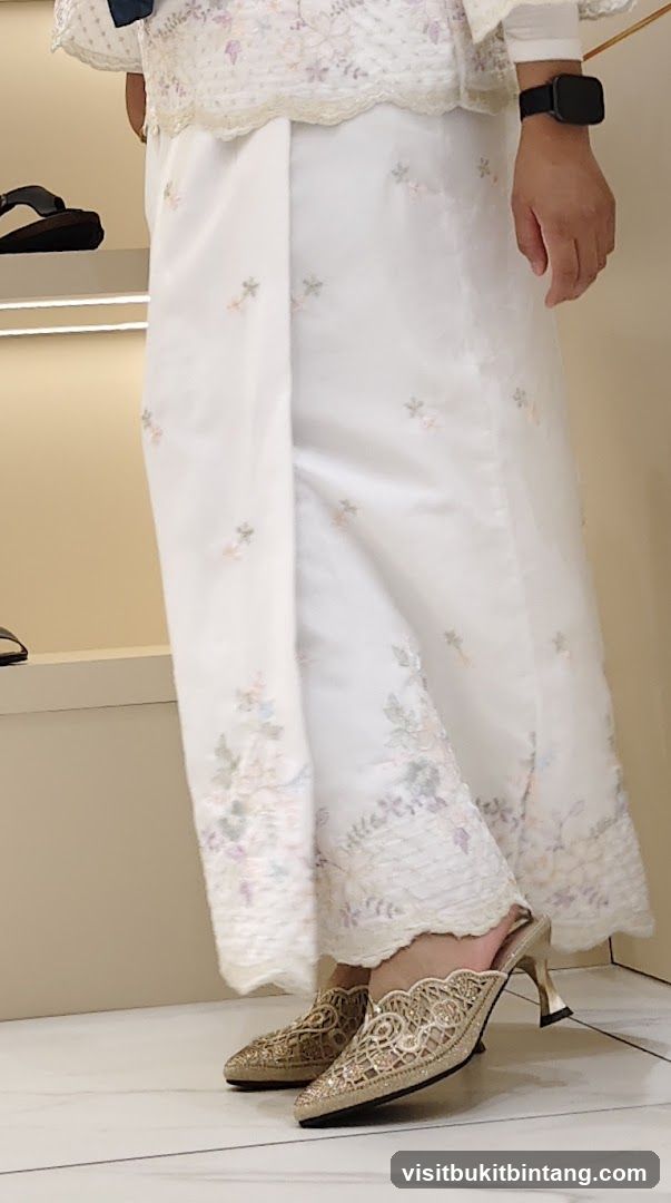 Woman wearing embroidered white outfit and gold heels