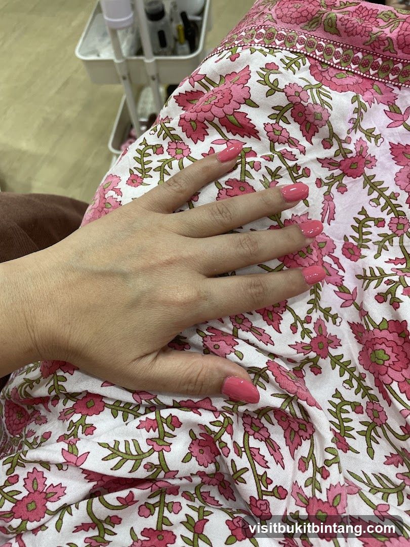 Woman's hand with pink nail polish resting on floral fabric