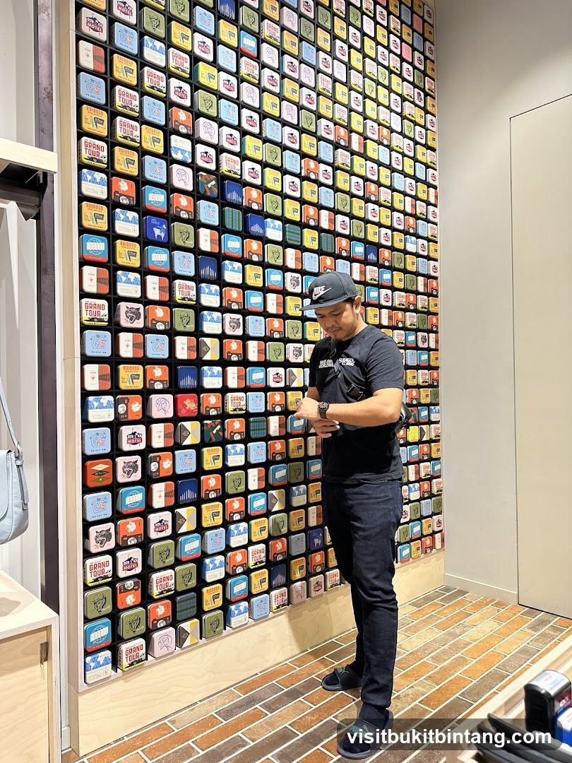 Man looking at watch in front of a wall display of small tins
