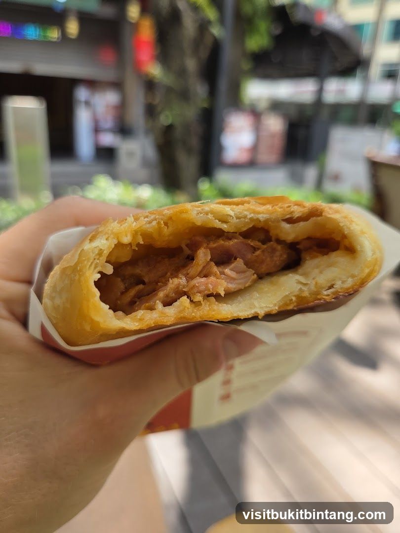 Hand holding a half-eaten pastry sandwich