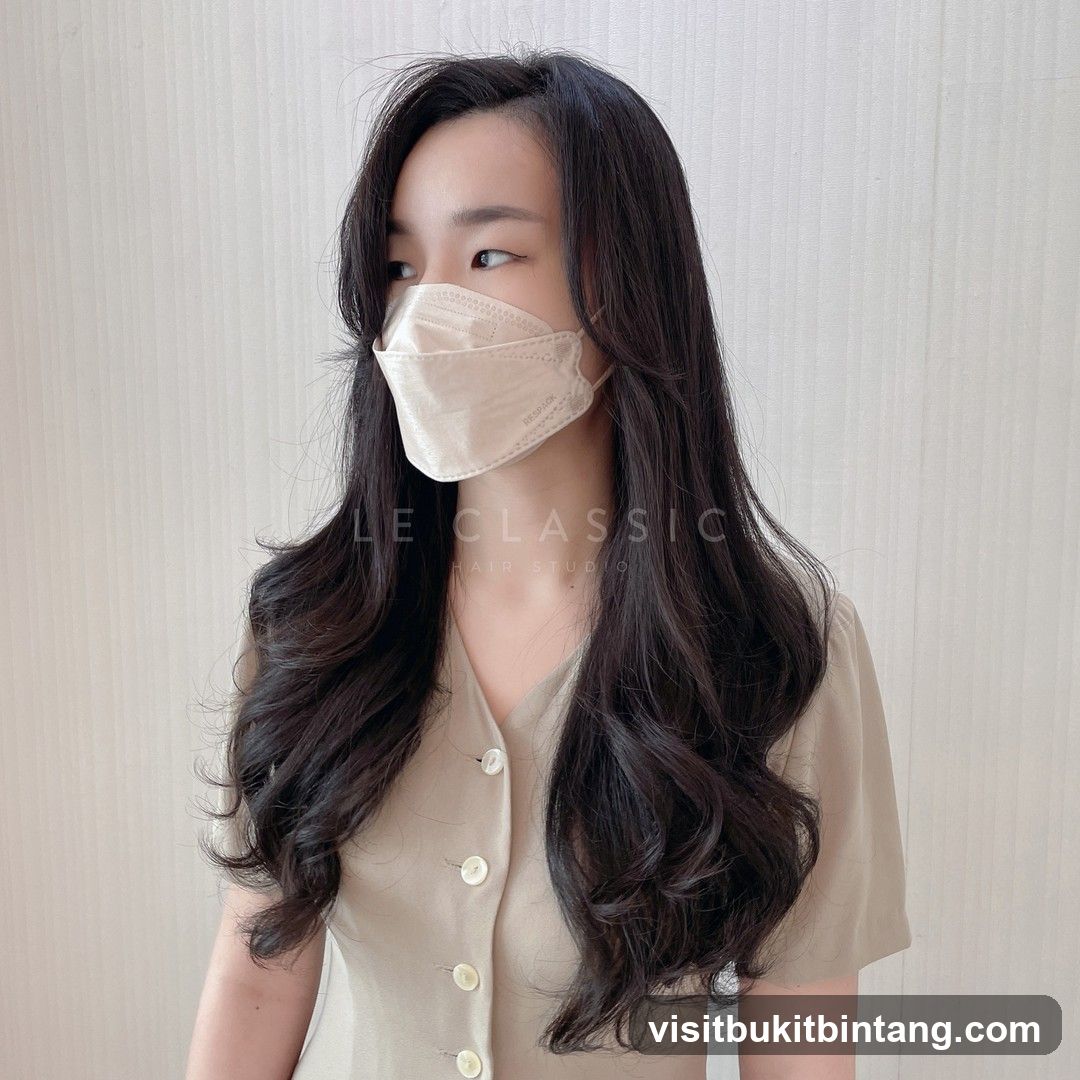 Woman with long, wavy dark hair and a beige mask