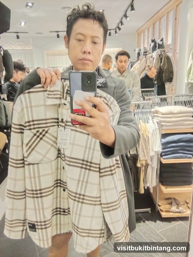 Man holding a plaid shirt in a clothing store