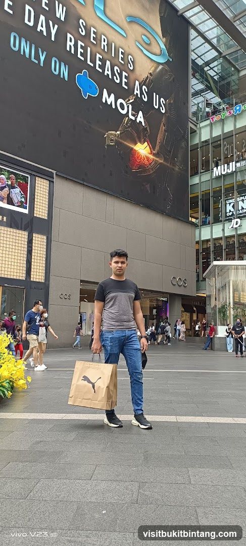 Man holding shopping bag in front of mall building