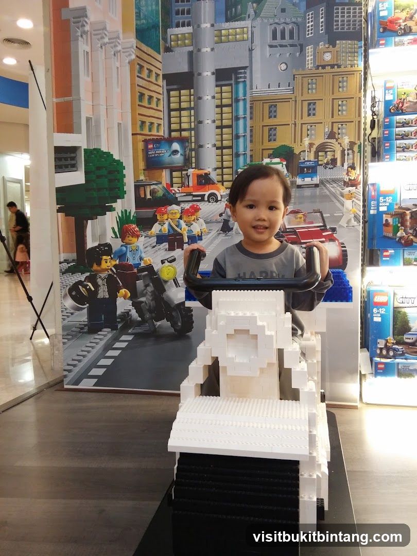Child sitting on a Lego motorcycle in front of a Lego city backdrop