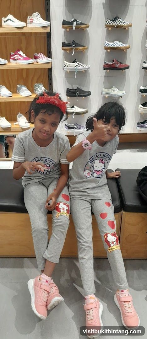 Two girls in Hello Kitty outfits giving thumbs up in a shoe store