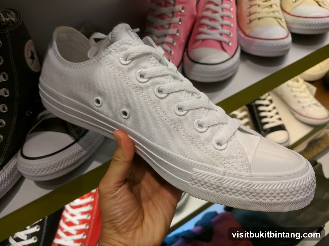 Hand holding white sneakers