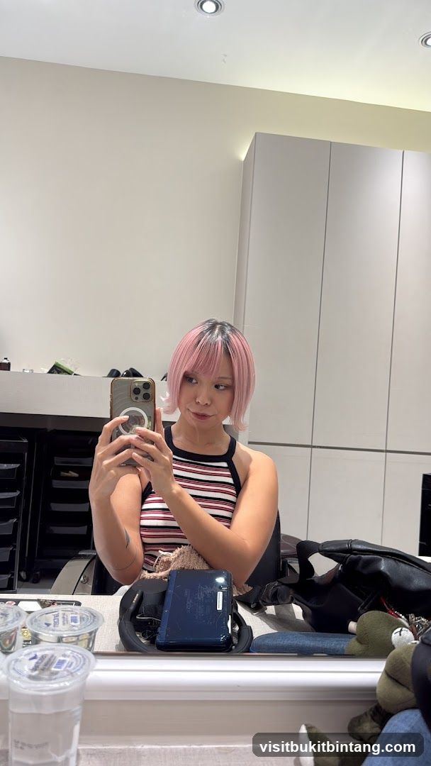 Woman taking a mirror selfie with pink hair