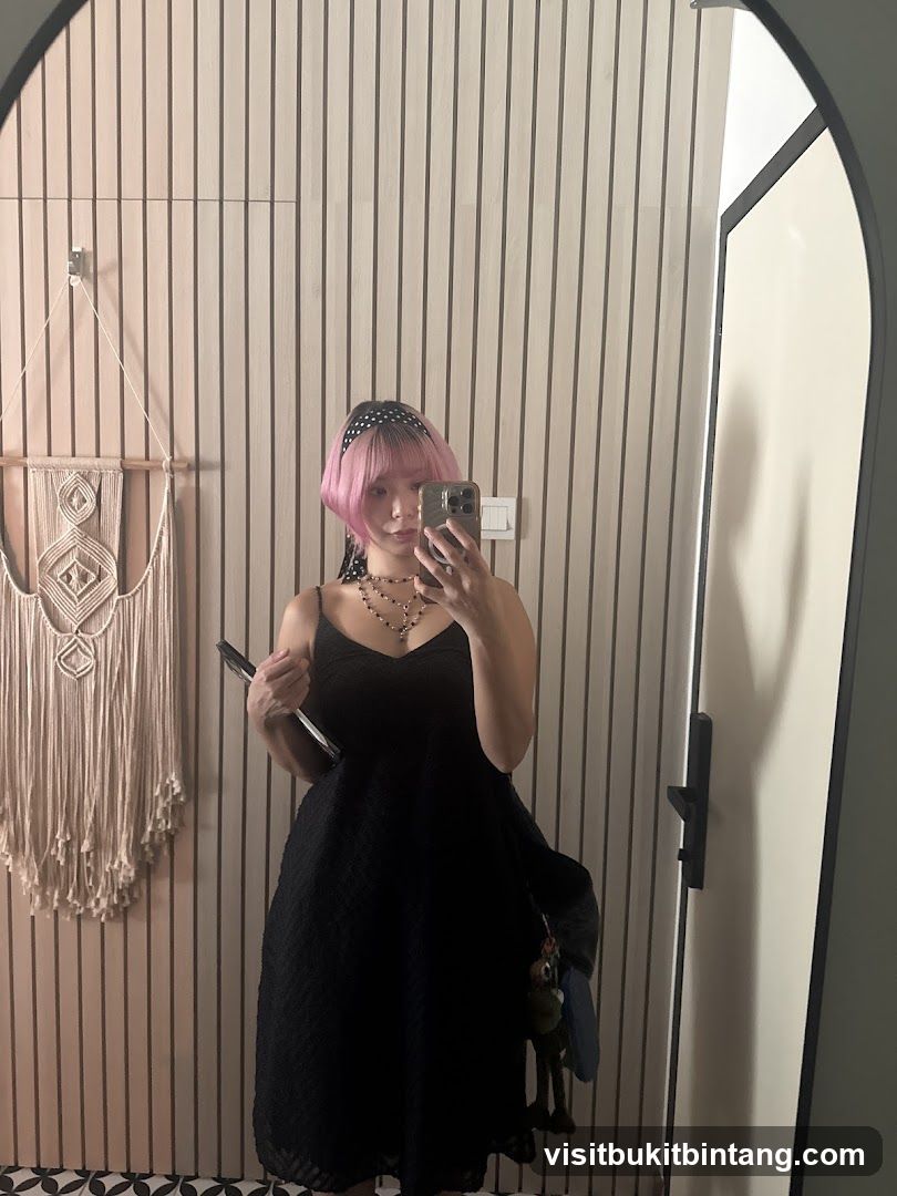 Woman in black dress taking a mirror selfie
