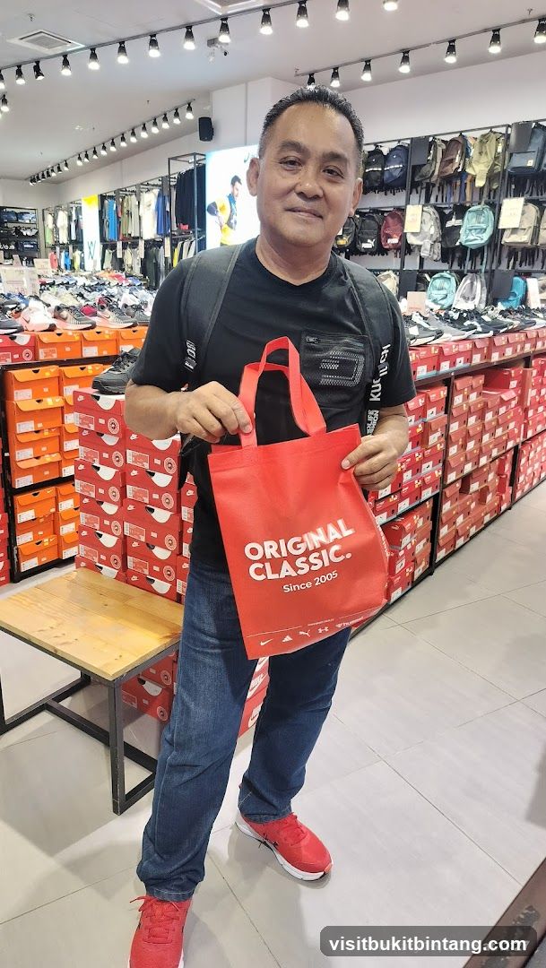 Man holding a red tote bag in a shoe store