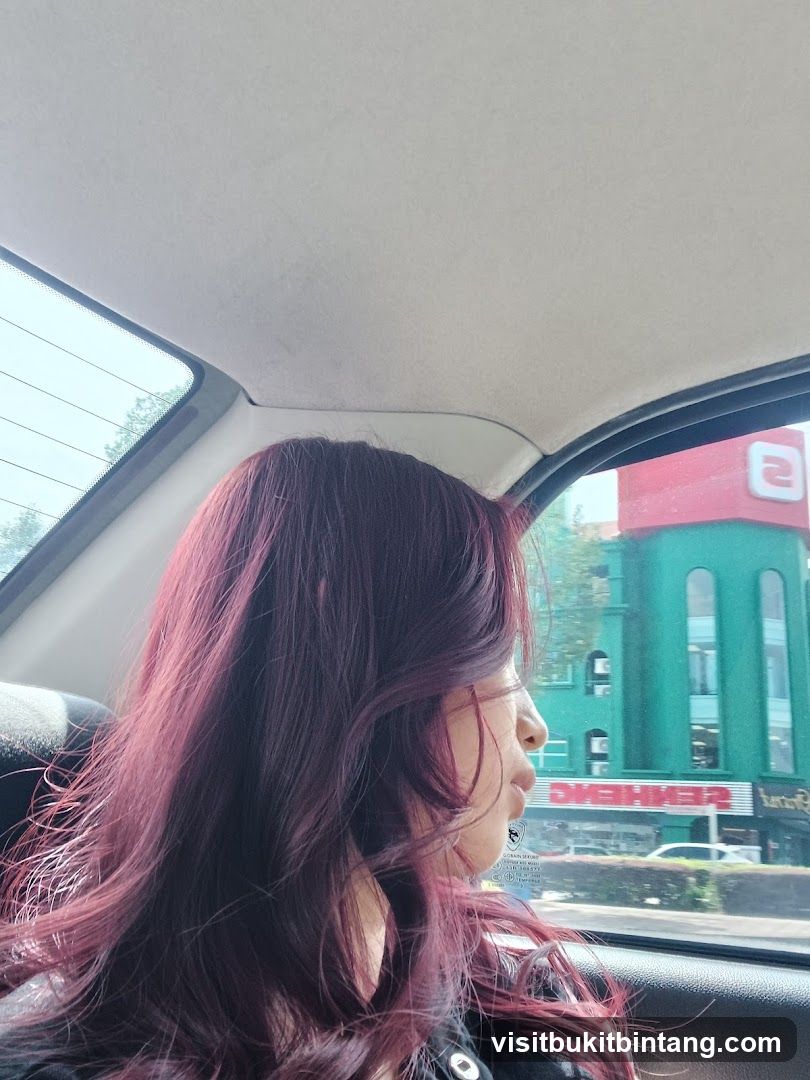 Woman looking out car window at green building