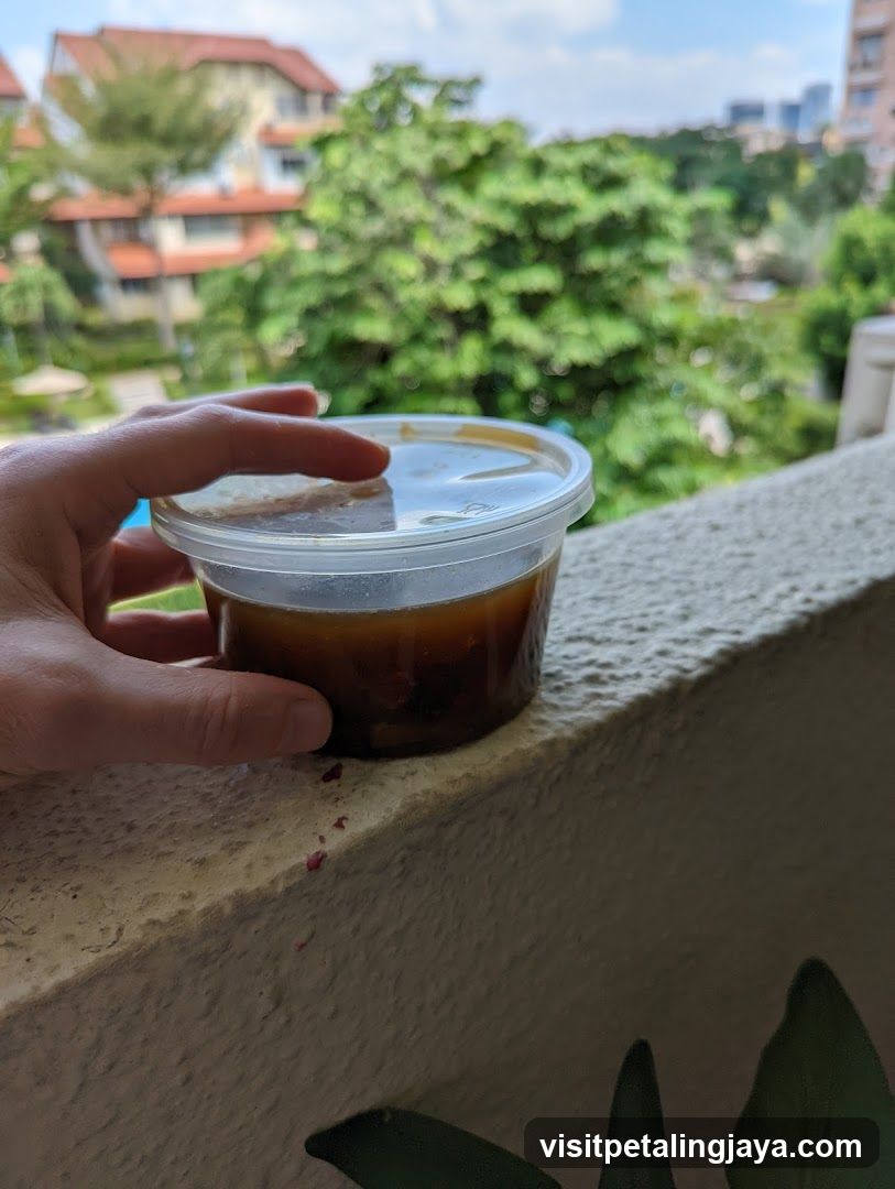 Hand holding a container of dark liquid on a balcony ledge