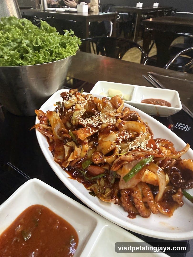 Korean-style stir-fried seafood dish with dipping sauces and lettuce