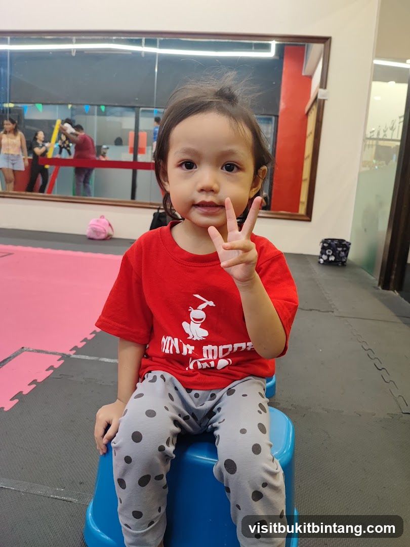Child in a red shirt and polka dot pants making a peace sign