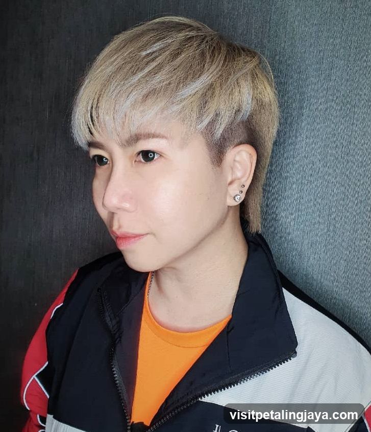 Portrait of person with short blonde hair and colorful jacket