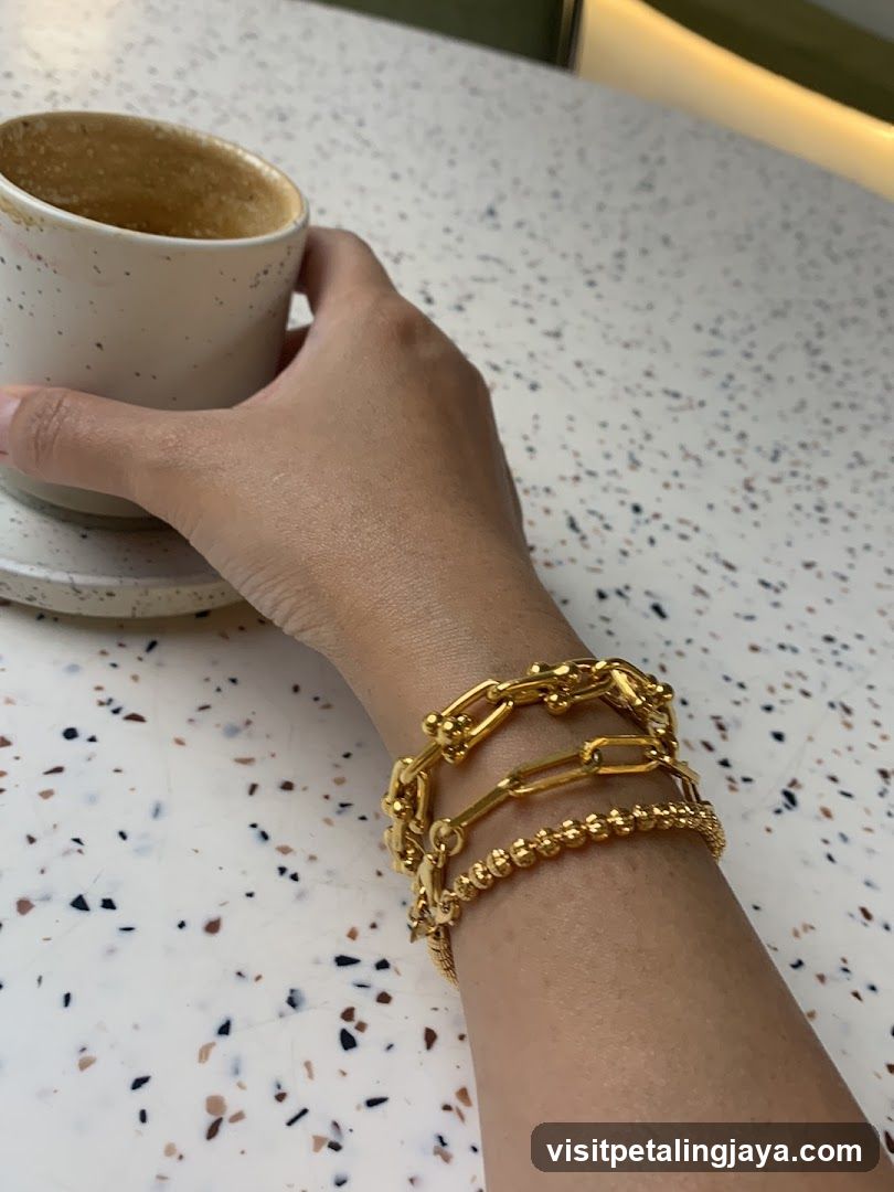 Hand holding coffee cup with gold bracelets