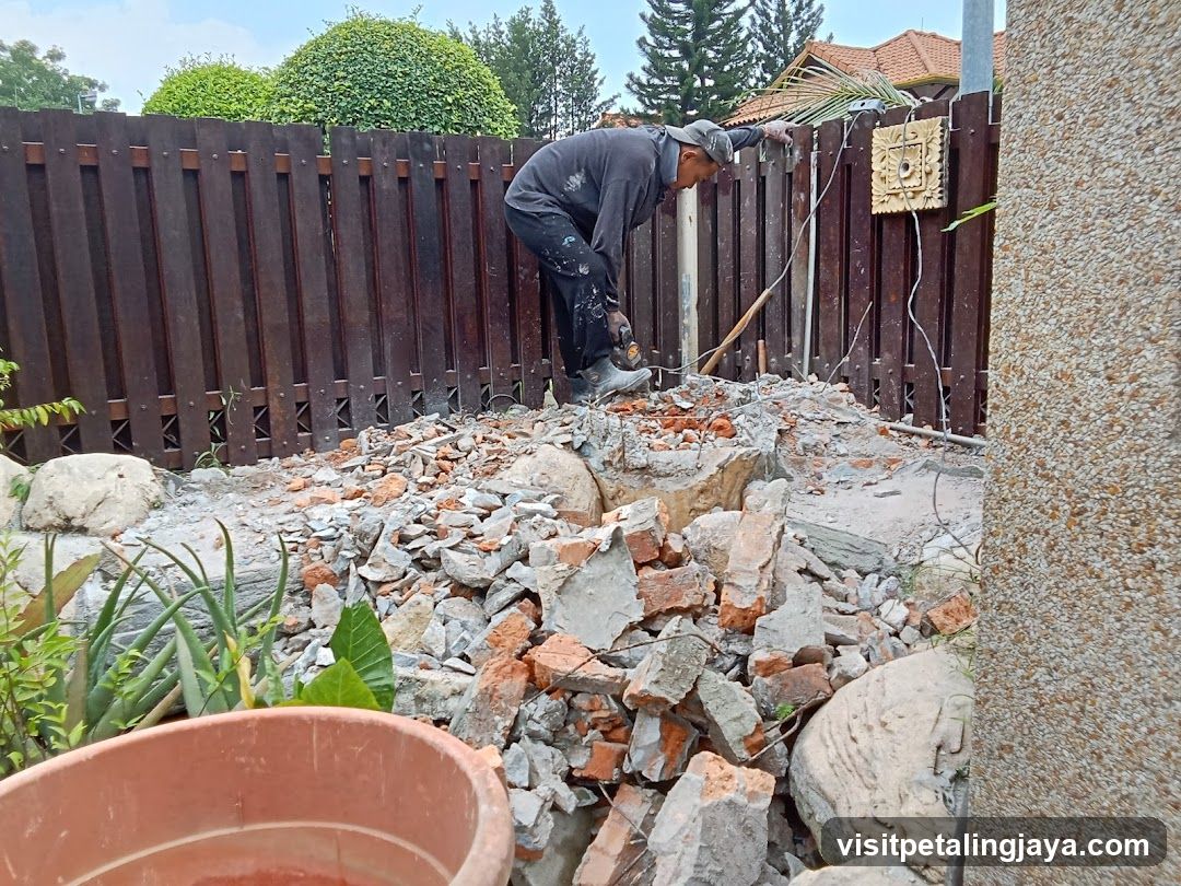 Worker demolishing fence and wall