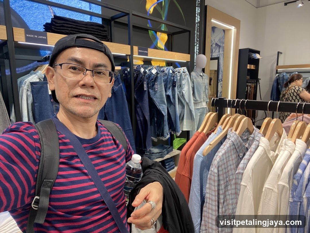 Man in striped shirt taking selfie inside clothing store