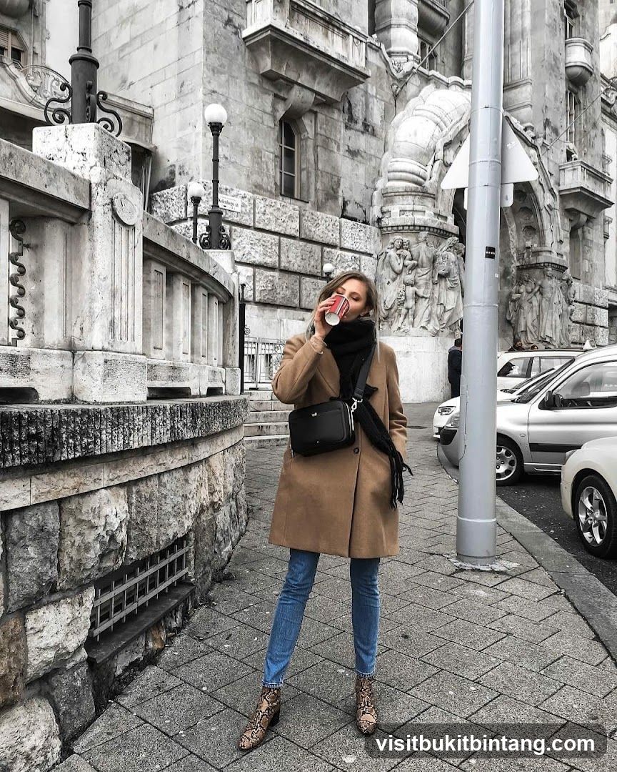 Woman drinking from a coffee cup on a city street