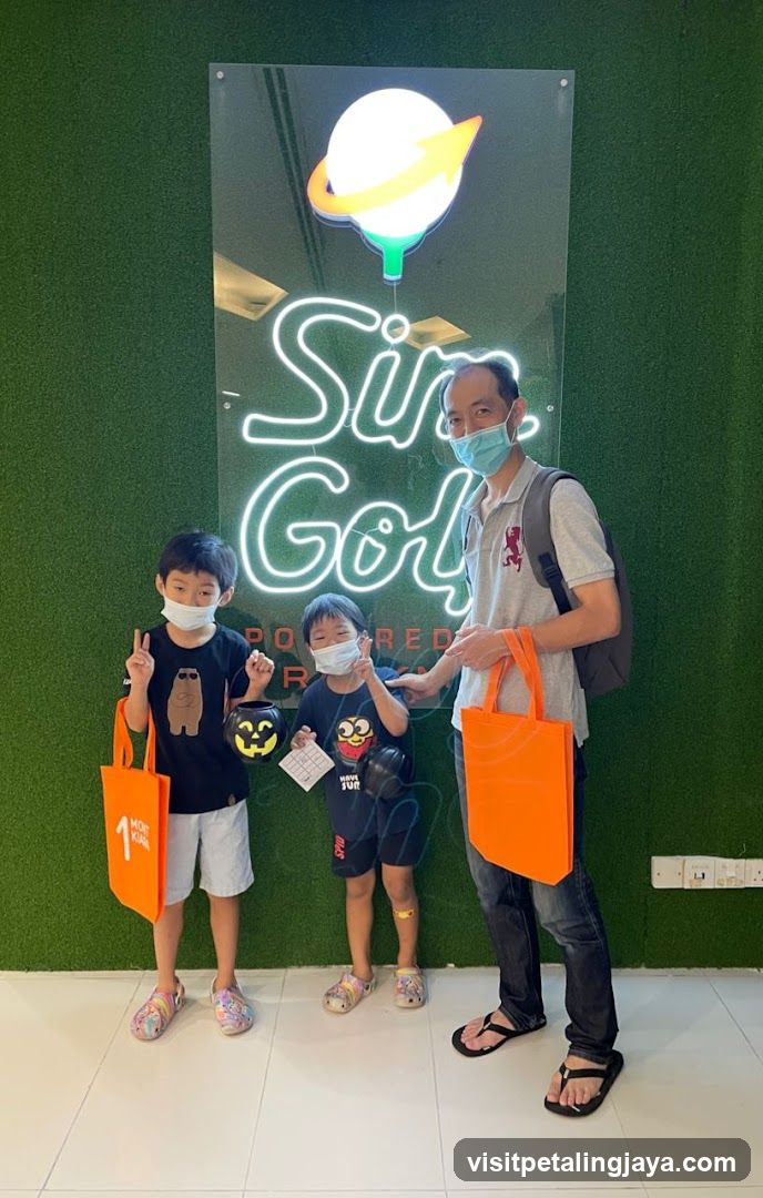 Family with orange bags in front of neon sign