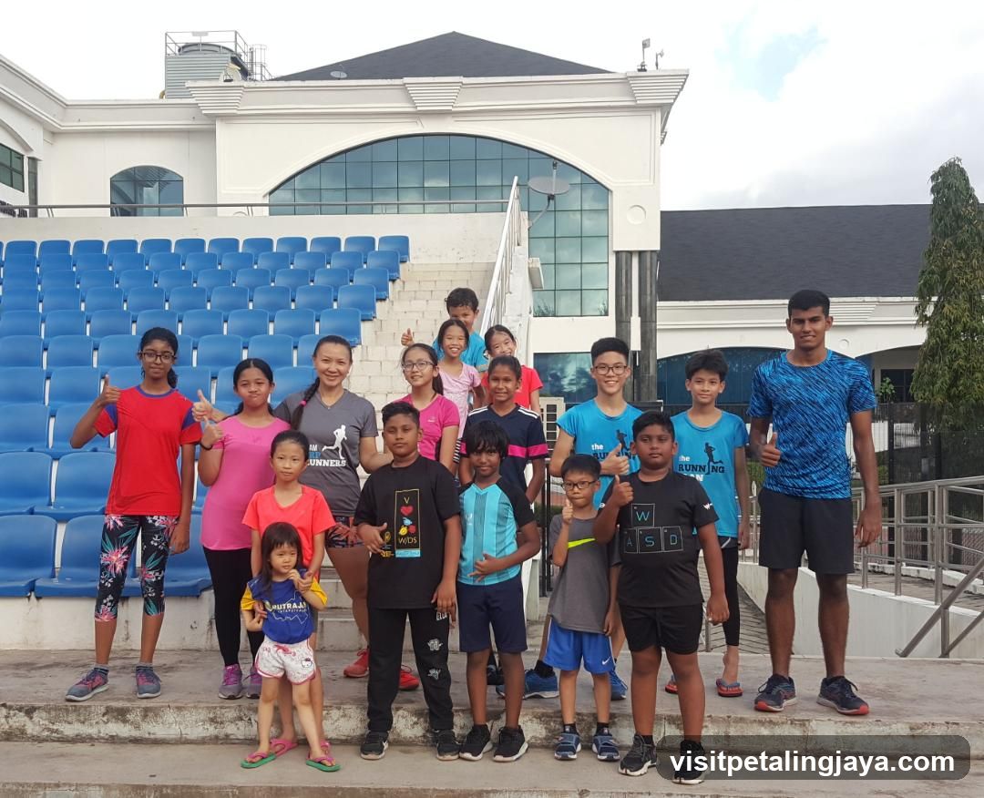Group of children and teens posing in front of a stadium