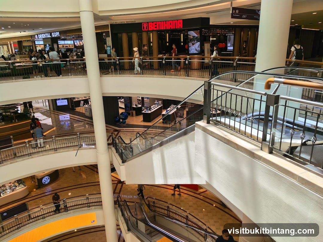 Multi-level shopping mall interior with escalators and various shops