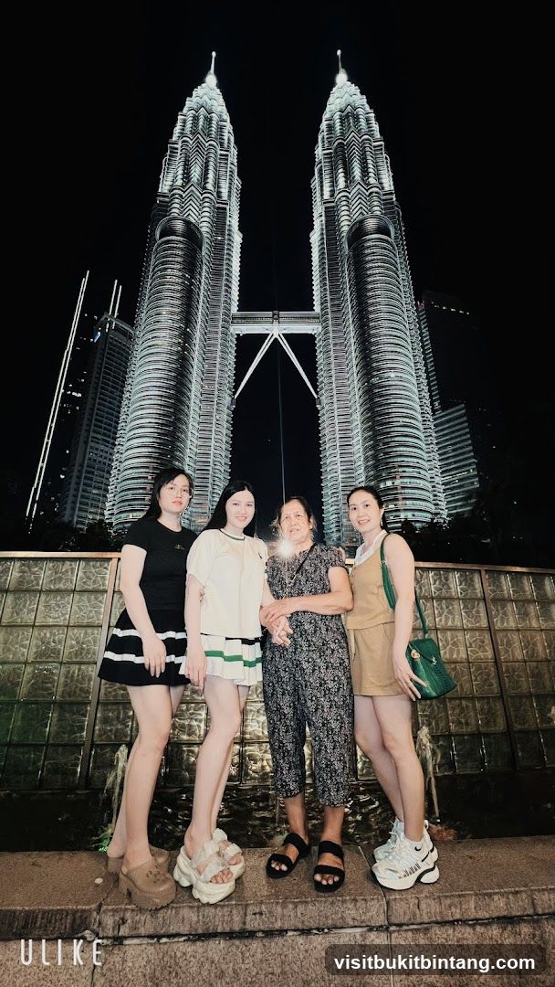 Four people posing in front of the Petronas Towers at night