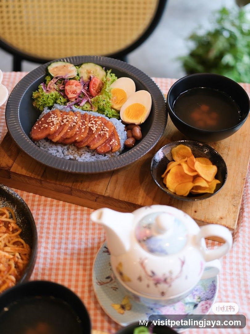 Bowl of food with rice, egg, and sides on a table