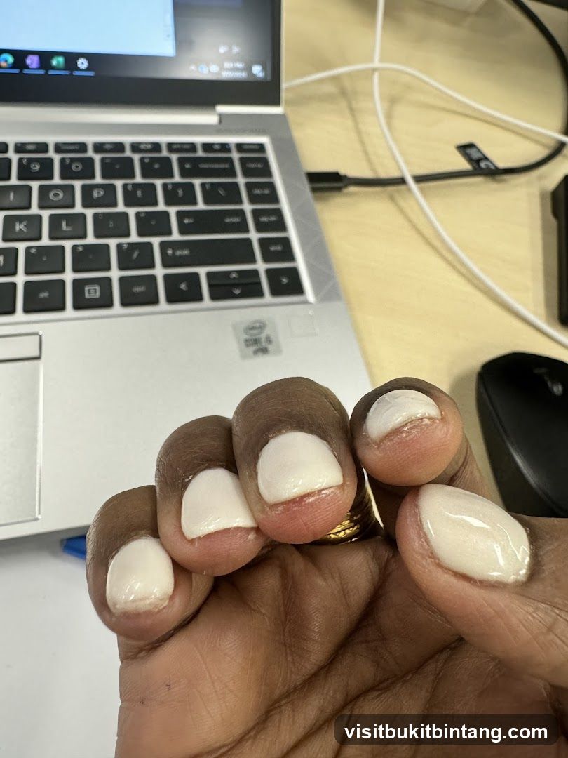 Hand with white nail polish near laptop