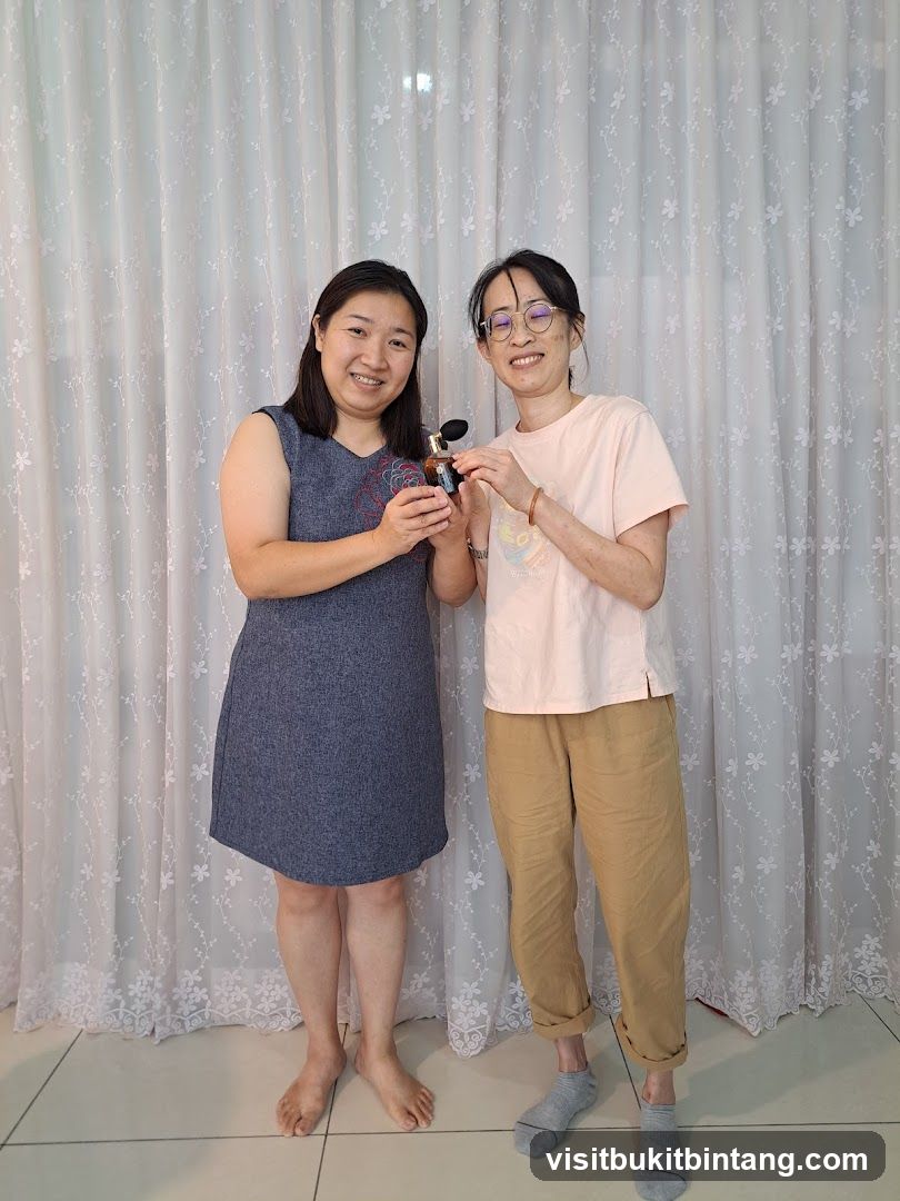 Two women holding a perfume bottle