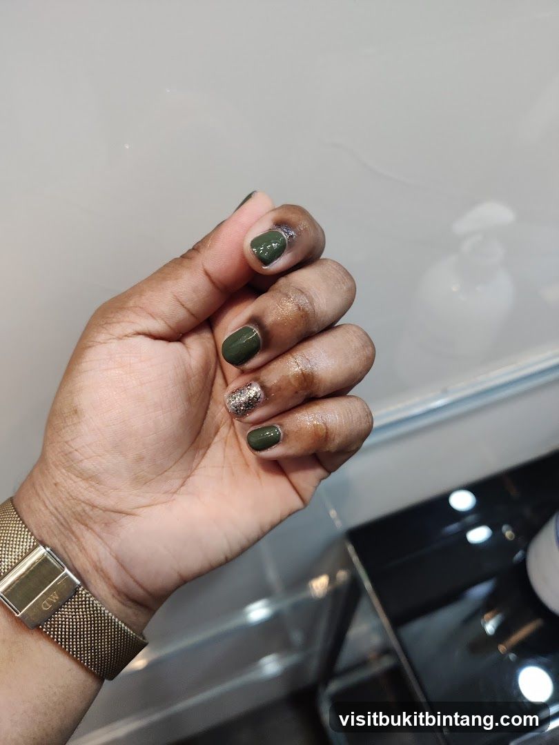 Hand with green and glitter nail polish